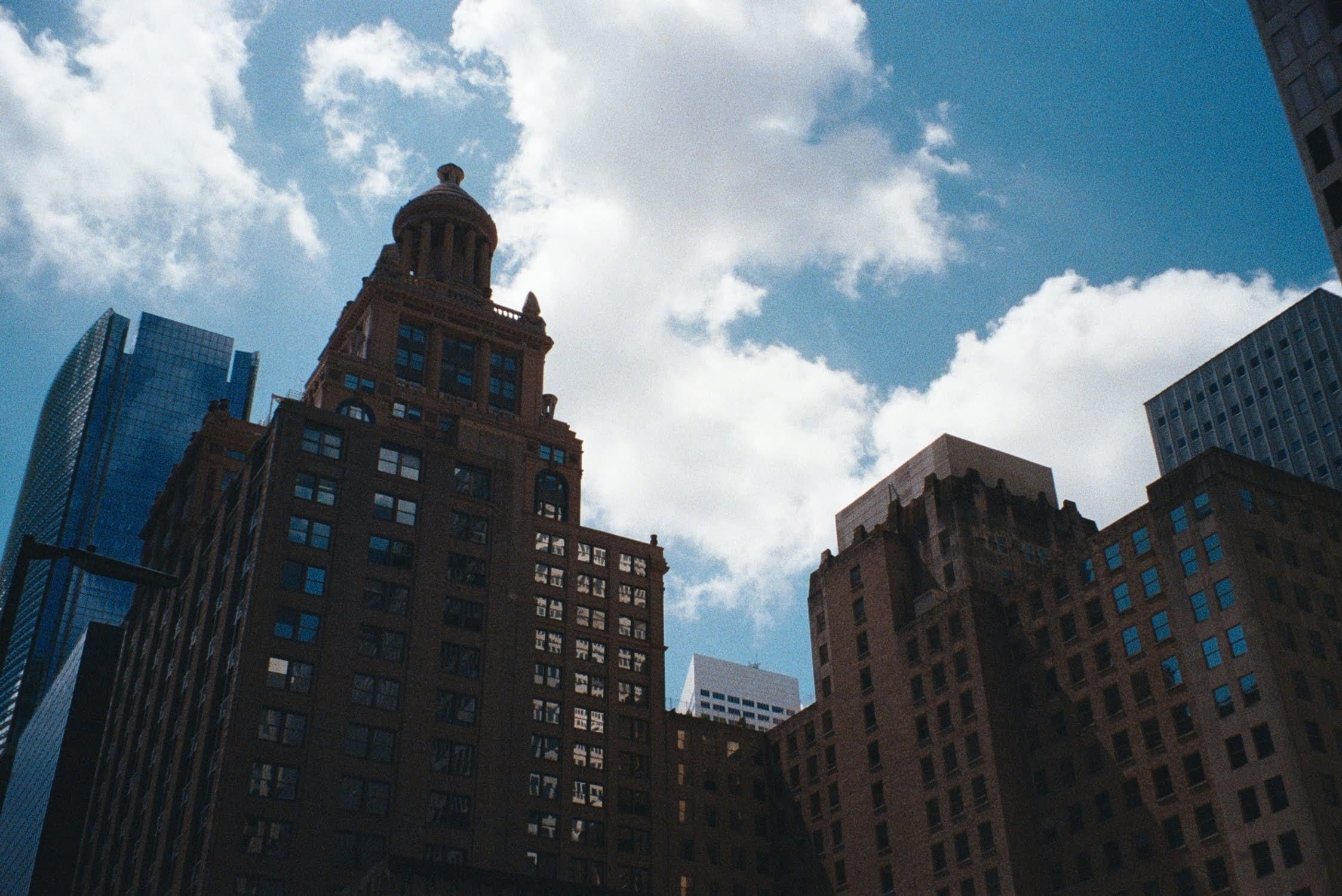 Les tours de brique du centre de Houston vues d'en bas, sur un ciel bleu aux nuages blancs