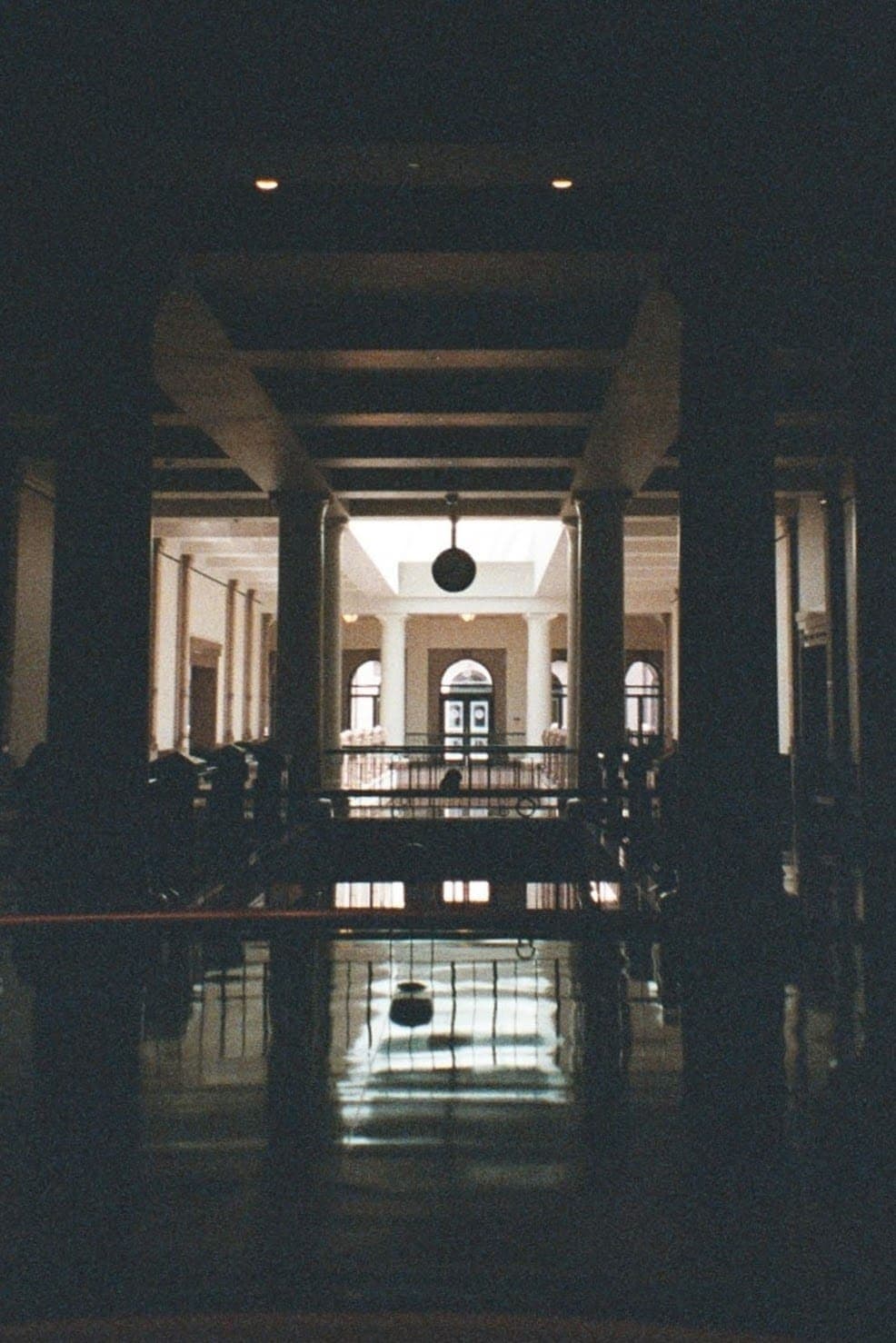 Un couloir sombre du Capitole du Texas qui s'ouvre sur une rotonde lumineuse, au sol qui reflète la lumière